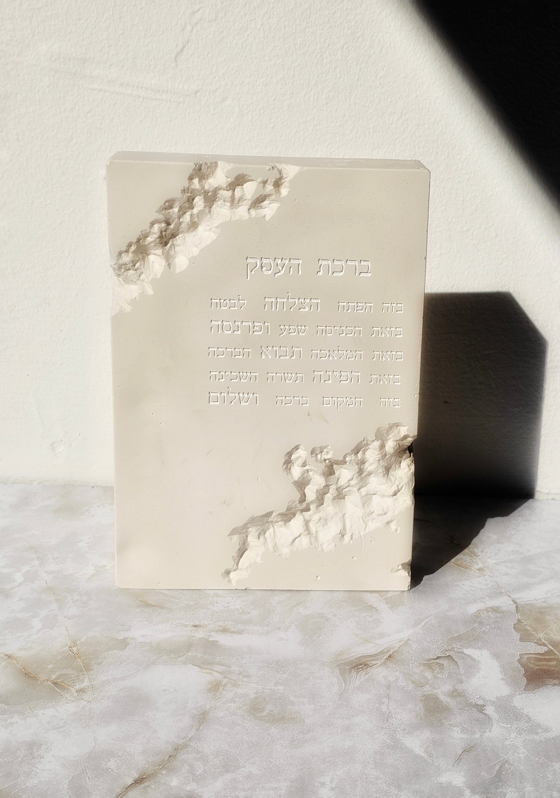 Handcrafted stone-look Birkat HaEsek plaque with engraved Hebrew business blessing, textured sculpted edges for modern decor.