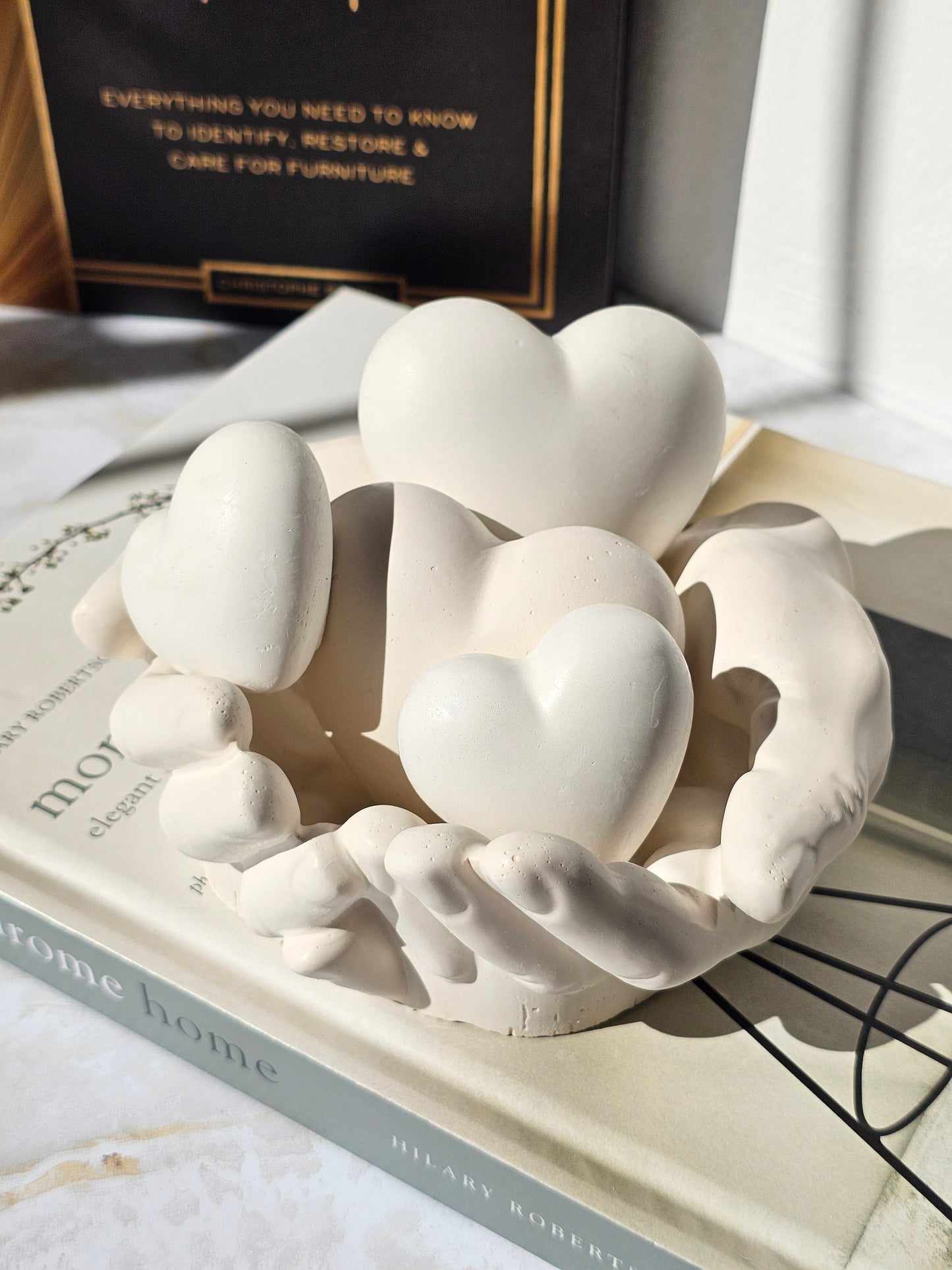 Handcrafted stone-look sculpture of hands gently holding multiple hearts, designed as a meaningful modern decor piece and sentimental gift.